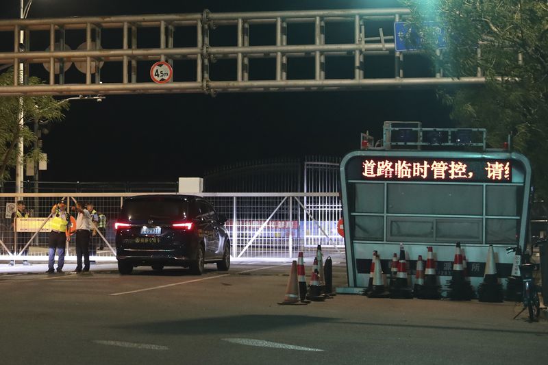 In this photo released by Xinhua News Agency, a policeman directs a motorist as authorities temporary close a road at Lingang new area of the China Pilot Free Trade Zone ahead of the landfall of Typhoon Bebinca in Shanghai, China, Sunday, Sept. 15, 2024. (Fang Zhe/Xinhua via AP)