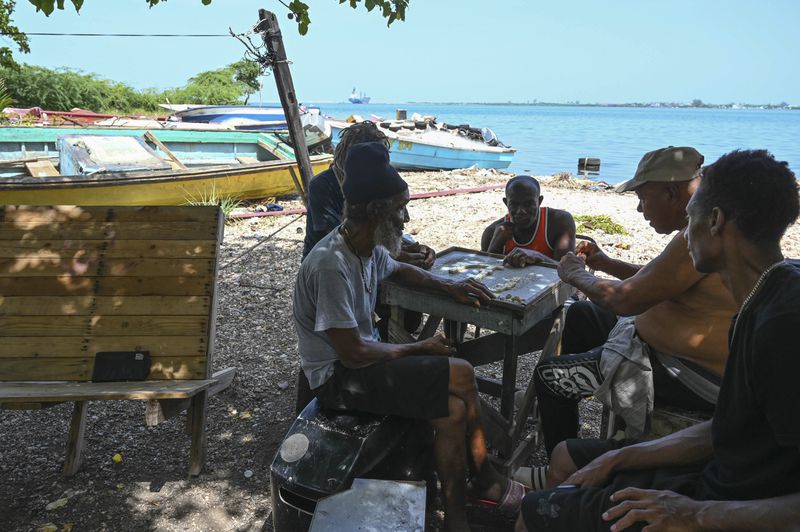 Fishermen play dominoes after pulling their boats out of the water to protect them from Hurricane Beryl in Kingston, Jamaica, Tuesday, July 2, 2024. (AP Photo/Collin Reid)