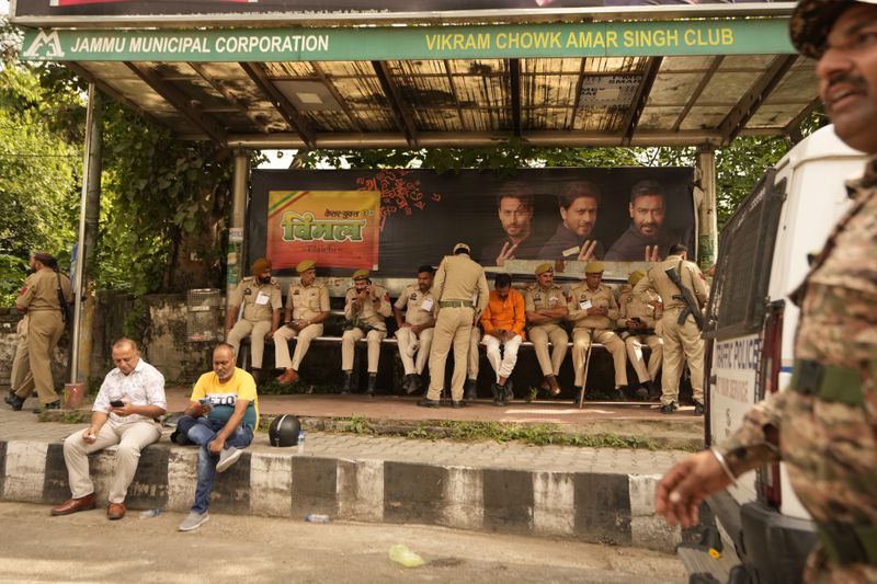 Security personnel take rest under a passenger shed outside a counting center in Jammu, India, Tuesday, Oct. 8, 2024. (AP Photo/Channi Anand)