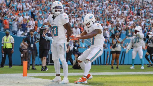 Miami Dolphins wide receiver Tyreek Hill (10) holds his hands behind his back as if he is handcuffed as Miami Dolphins wide receiver Jaylen Waddle (17) unlocks them after Hill scores against the Jacksonville Jaguars in the second half during an NFL football game at Hard Rock Stadium in Miami Gardens, Florida, on Sunday, Sept. 8, 2024. (Al Diaz/Miami Herald via AP)