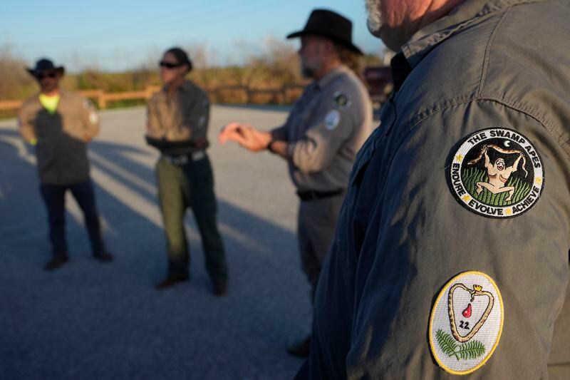 Members of the Swamp Apes, a veterans therapy nonprofit, gather as they wait for sunset to hunt invasive Burmese pythons, Tuesday, Aug. 13, 2024, in the Florida Everglades. (AP Photo/Wilfredo Lee)