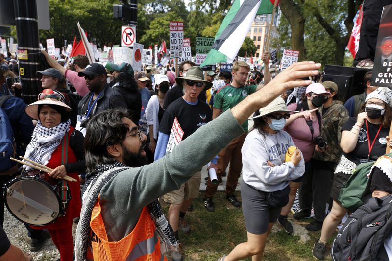 YM Masood, front, left, a 20-year-old college student and activist, directs pro-Palestinian protesters at the March on DNC on Monday, Aug. 19, 2024, in Chicago, serving as one of several volunteer marshals at the parade to help keep marchers organized and deescalate potential conflict. (AP Photo/Martha Irvine)