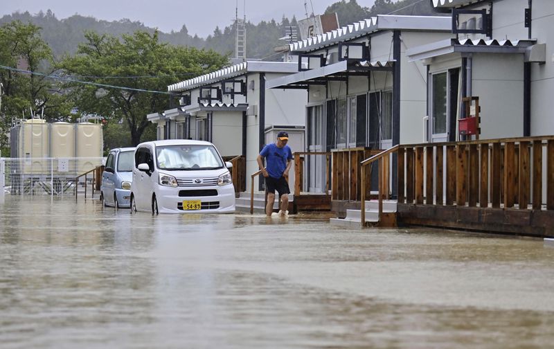 A man wades through a flooded street near temporary housing units installed after the Jan. 1 earthquake in Wajima, Japan, Sunday, Sept. 22, 2024, following heavy rain in central Japan's Noto peninsula area. (Muneyuki Tomari/Kyodo News via AP)