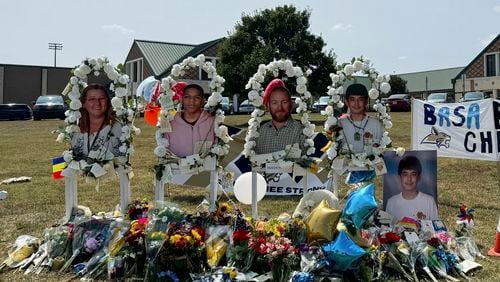 A poster with images of shooting victims from left, Cristina Irimie, Mason Schermerhorn, Richard Aspinwall and Christian Angulo is displayed at a memorial outside Apalachee High School, Tuesday, Sept. 10, 2024, in Winder, Ga. (AP Photo/Charlotte Kramon)