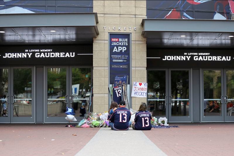 Shiloh Rivera, left, mourns with Hylas Stemen, center, and Amanda Rivera of Columbus at a memorial set up by fans for Blue Jackets hockey player Johnny Gaudreau in Columbus, Ohio, Aug. 30, 2024. Gaudreau, along with his brother Matthew, was fatally struck by a motorist while riding his bicycle on Thursday. (AP Photo/Joe Maiorana)