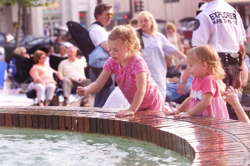 Aug. 24, 2001: Enjoying an evening in the park, 5-year-old Brie Withrow, center, plays in the fountain at Marietta Square with her little sister, Paige Withrow, right, before a musical performance.