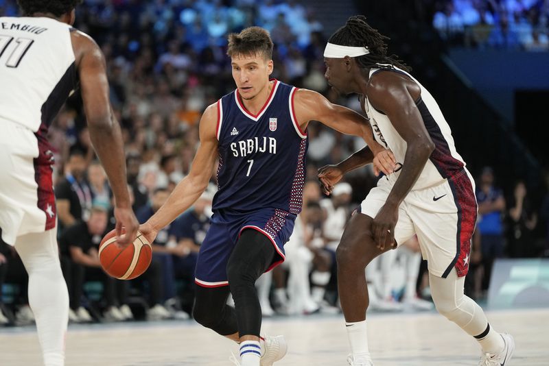 Bogdan Bogdanovic (7), of Serbia drives past United States' Jrue Holiday (12) during a men's semifinals basketball game at Bercy Arena at the 2024 Summer Olympics, Thursday, Aug. 8, 2024, in Paris, France. (AP Photo/Michael Conroy)