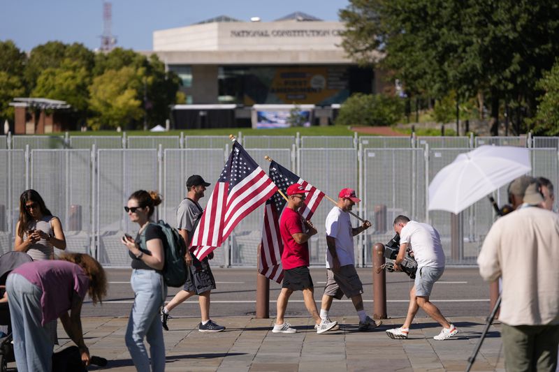 People gather across the street from the National Constitution Center, the site of tonight's presidential debate between Republican presidential nominee former President Donald Trump and Democratic presidential nominee Vice President Kamala Harris, Tuesday, Sept. 10, 2024, in Philadelphia. (AP Photo/Matt Slocum)