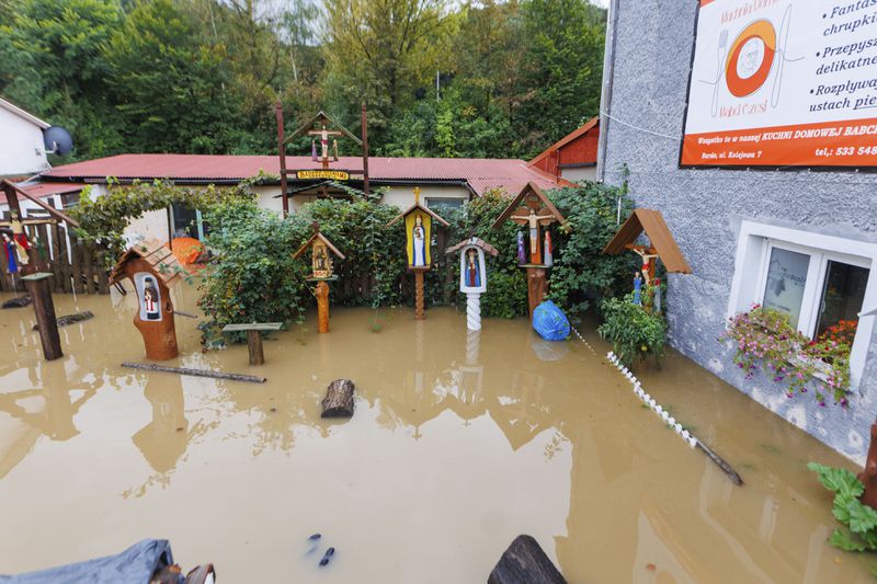 A flooded backyard with carved wood religious figures in Kłodzko, southwest Poland, as days of unusually heavy rain have swollen rivers and spilled over embankments in the region, on Sunday, Sept. 15, 2024. (AP Photo/Krzysztof Zatycki)