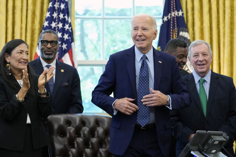 President Joe Biden, who is joined by civil rights leaders, community members, and elected officials, stands up after signing a proclamation in the Oval Office of the White House in Washington, Friday, Aug. 16, to designate the Springfield 1908 Race Riot National Monument. (AP Photo/Susan Walsh)