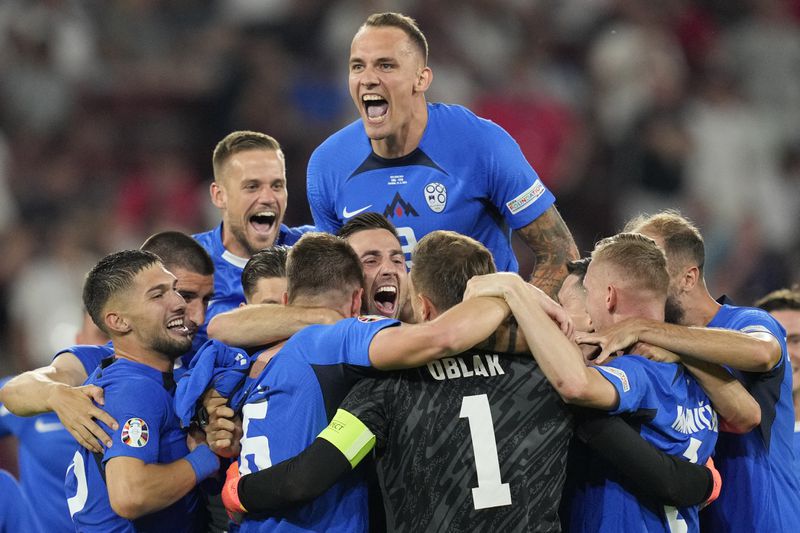 Slovenia's players celebrate at the end of a Group C match between the England and Slovenia at the Euro 2024 soccer tournament in Cologne, Germany, Tuesday, June 25, 2024. (AP Photo/Andreea Alexandru)