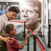 Superintendent of Martin Luther King, Jr. National Historical Park Judy Forte talks with Andre Thomas,7, about the images in a new exhibit that shows the connection between King and President Jimmy Carter Tuesday, Feb. 28, 2023.  (Steve Schaefer/steve.schaefer@ajc.com)
