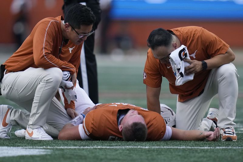 Texas quarterback Quinn Ewers, center, is helped after an injury during the first half of an NCAA college football game against UTSA in Austin, Texas, Saturday, Sept. 14, 2024. (AP Photo/Eric Gay)