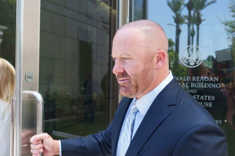 Mathew Bowyer, a Southern California bookbinder, opens the door for his attorney as he enters the federal courthouse in Santa Ana, Calif., Friday, Aug. 9, 2024. (AP Photo/Damian Dovarganes)