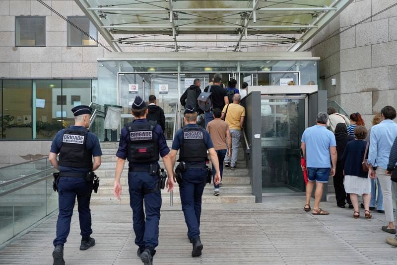 FILE - Police officers walk in the Avignon court house prior to the trial of Dominique Pelicot, in Avignon, southern France, Thursday, Sept. 5, 2024. (AP Photo/Lewis Joly, File)