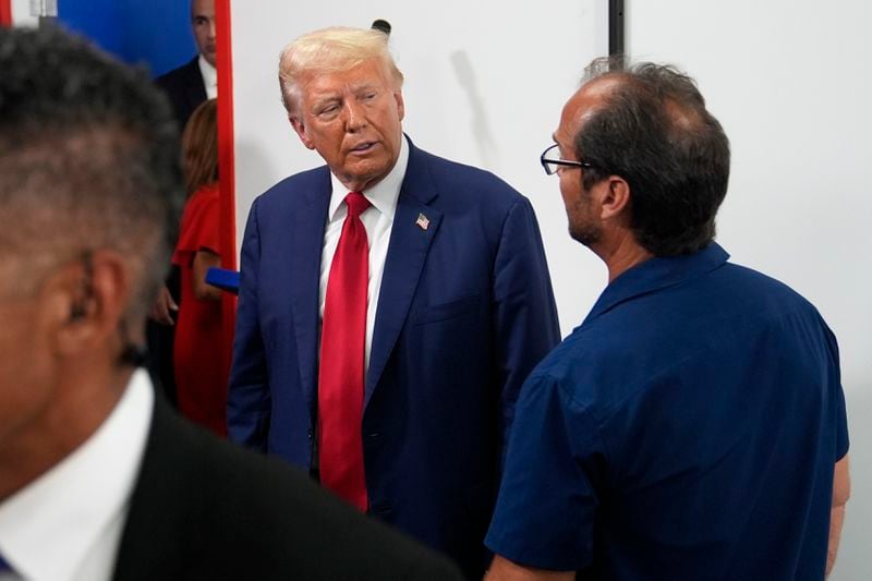 Republican presidential nominee former President Donald Trump, left, speaks with a supporter during a stop at a campaign office, Monday, Aug. 26, 2024, in Roseville, Mich. (AP Photo/Carolyn Kaster)