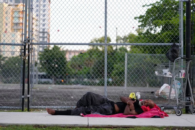 A person sleeps on the sidewalk on the first day of a statute that took effect, making it illegal in Florida to sleep on sidewalks, in parks, on beaches or in other public spaces — one of the country's strictest anti-homelessness laws, Tuesday, Oct. 1, 2024, in Fort Lauderdale, Fla. (AP Photo/Lynne Sladky)