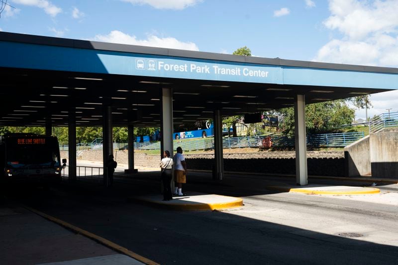 Commuters wait for a bus outside the Forest Park Blue Line train station in Forest Park, Ill., which remains closed, after four people were fatally shot on the train early Monday, Sept. 2, 2024. (Pat Nabong/Chicago Sun-Times via AP)