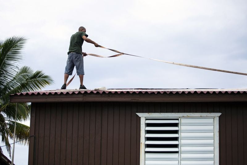 A man uses straps to tie down the roof of his home in Yabucoa, Puerto Rico, as Hurricane Dorian approaches on Wednesday, Aug. 28, 2019. It’s expected to hit the U.S. coast over Labor Day weekend. ERIKA P. RODRIGUEZ / THE NEW YORK TIMES