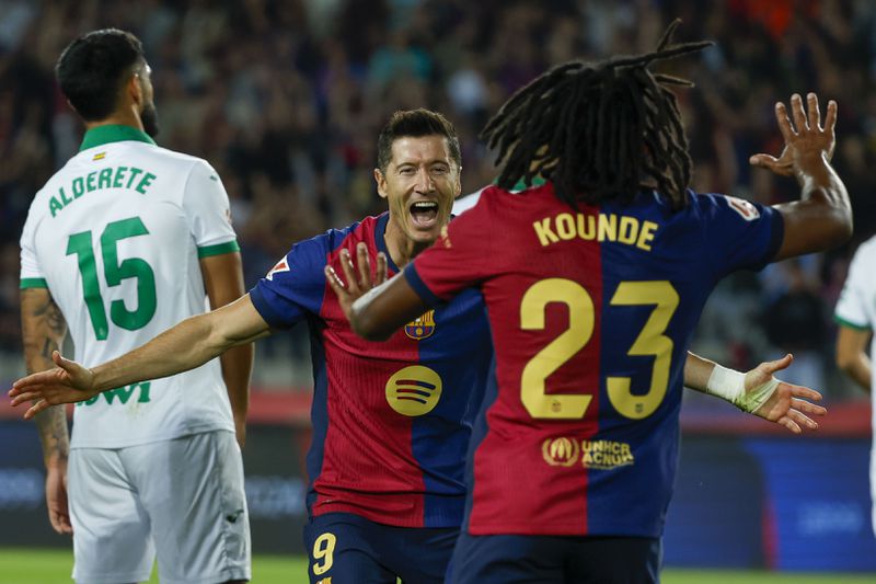 Barcelona's Robert Lewandowski, center, celebrates with Barcelona's Jules Kounde, front, after scoring the opening goal during a Spanish La Liga soccer match between Barcelona and Getafe at the Olympic stadium in Barcelona, Spain, Wednesday, Sept. 25, 2024. (AP Photo/Joan Monfort)