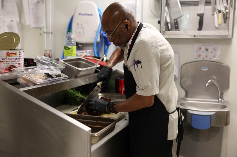 Kevin Oakes, cuts a rosemary pork loin with rosemary au jus in the kitchen of the United States Olympic and Paralympic Committee's High Performance Center during the Paralympic Games in Paris on Saturday, Aug. 31, 2024. Oakes has worked with the USOPC in Colorado Springs for three years. Oaks said that coming to Paris for the 2024 Olympic and Paralympic Games was his first time out of the country. "You don't go into working in a restaurant thinking you're gonna travel the world," Brian Knutson, director of food and nutrition for the USOPC said. (AP Photo/Nathalee Simoneau)