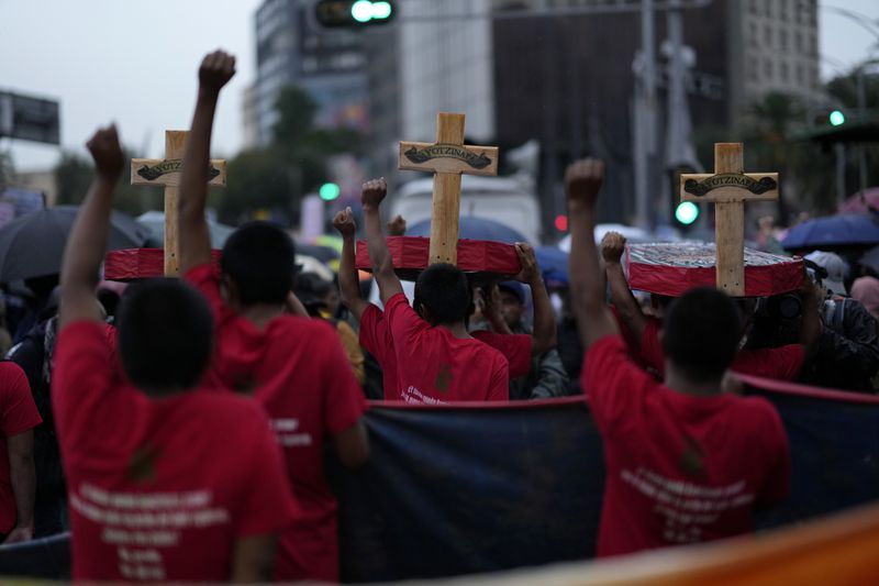 Youths raise their fists in unison as they take part in a demonstration marking the 10-year anniversary of the disappearance of 43 students from an Ayotzinapa rural teacher's college, in Mexico City, Thursday, Sept. 26, 2024. (AP Photo/Eduardo Verdugo)