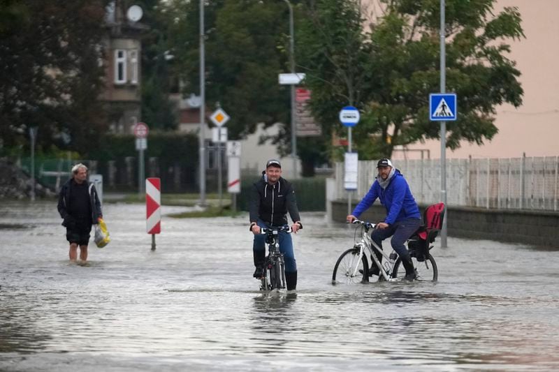 Residents ride bicycles through a flooded street in Litovel, Czech Republic, Monday, Sept. 16, 2024. (AP Photo/Petr David Josek)