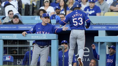 Texas Rangers' Adolis Garcia, right, celebrates with manager Bruce Bochy after scoring off a single hit by Wyatt Langord during the first inning of a baseball game against the Los Angeles Dodgers, Thursday, June 13, 2024, in Los Angeles. (AP Photo/Ryan Sun)