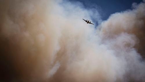 An air tanker soars through a large plume of smoke over and around wildfire-affected areas in the village of Ruidoso, N.M., Tuesday, June 18, 2024. (Chancey Bush/The Albuquerque Journal via AP)