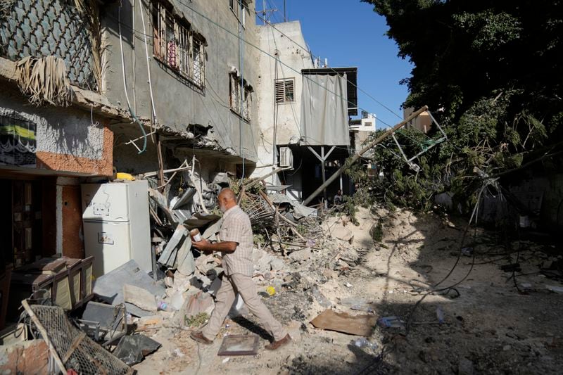 Palestinian refugees walk outside their partly destroyed houses in the West Bank refugee camp of Tulkarem, Thursday, Sept. 12, 2024. (AP Photo/Nasser Nasser)