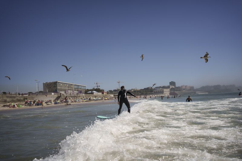 A member of Surf Church surfs before a worship service in Matosinhos beach in the suburbs of Porto, Portugal, Sunday, Aug. 18, 2024. (AP Photo/Luis Andres Henao)