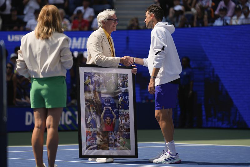 Dominic Thiem, of Austria, is presented with a collage of photos of his play at the U.S. Open over the years after losing to Ben Shelton, of the United States, during the first round of the U.S. Open tennis championships, Monday, Aug. 26, 2024, in New York. (AP Photo/Seth Wenig)