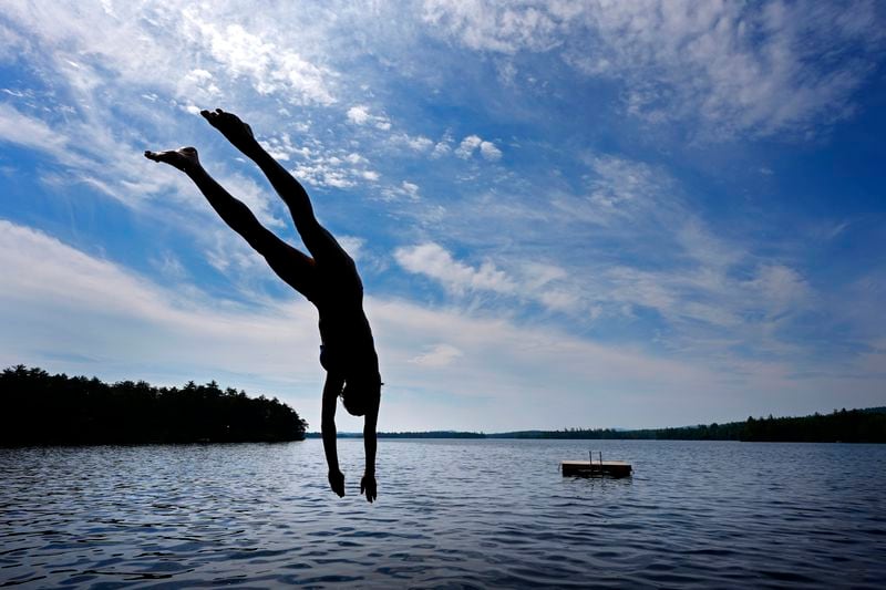 Melana Price, of Southfield, Mich., dives into Squam Lake at Rockywold Deephaven Camps, Thursday, June 20, 2024, in Holderness, N.H. Ice harvested from the lake in winter is used to refrigerate guest's ice boxes throughout the summer season. (AP Photo/Robert F. Bukaty)