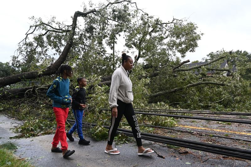 Angel Coney with her two sons, Travi (left), 10, and Mari, 9, check out fallen trees and wires caused by Hurricane Helene in front of their house, Friday, September 27, 2024 in Dublin. (Hyosub Shin / AJC)