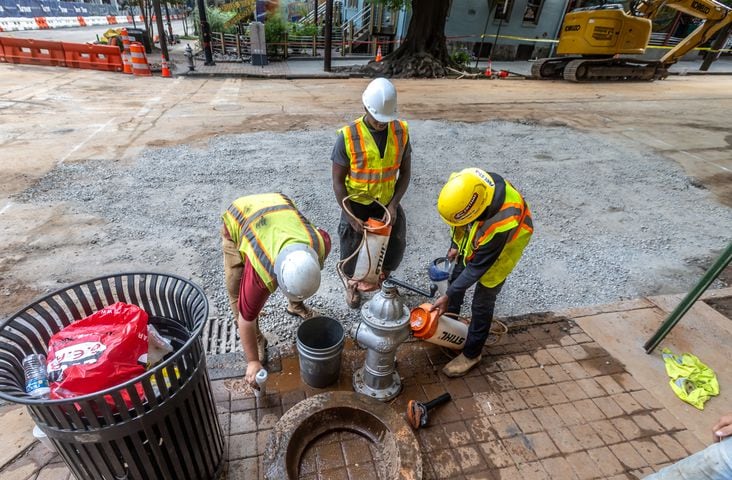 Workers continued to put the finishing touches on the filled in water main hole Wednesday morning, June 5, 2024 following the city’s announcement that water had been restored following the break on West Peachtree Street and 11th Street. The city said the system was being brought back online slowly to “allow system pressures to build.” (John Spink/AJC)