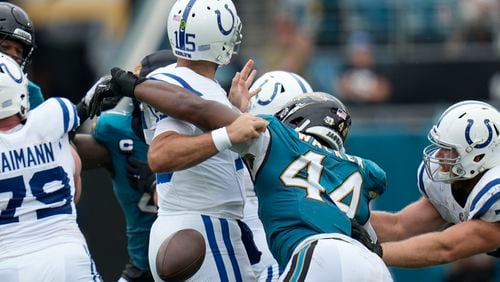 Indianapolis Colts quarterback Joe Flacco (15) fumbles as he is hit by Jacksonville Jaguars' Travon Walker (44) during the first half of an NFL football game, Sunday, Oct. 6, 2024, in Jacksonville, Fla. (AP Photo/John Raoux)