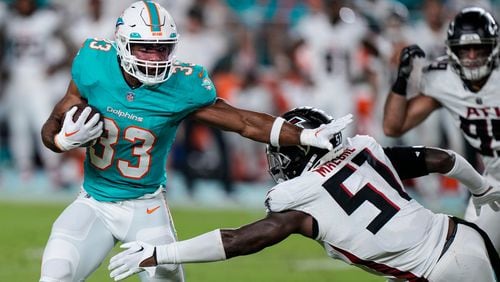 Miami Dolphins running back Chris Brooks (33) tries to escape from Atlanta Falcons linebacker DeAngelo Malone (51) in the second half of a preseason NFL football game, Friday, Aug. 11, 2023, in Miami Gardens, Fla. (AP Photo/Wilfredo Lee)