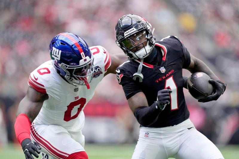 Houston Texans wide receiver Stefon Diggs (1) picks up a first down before being stopped by New York Giants linebacker Brian Burns (0) in the first half of a preseason NFL football game, Saturday, Aug. 17, 2024, in Houston. (AP Photo/Eric Gay)