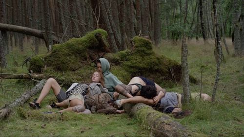 Dancers rest against the mossy surfaces of a dark forest in the dance film "Songs from the Compost," on view at the Michael C. Carlos Museum through May 19.