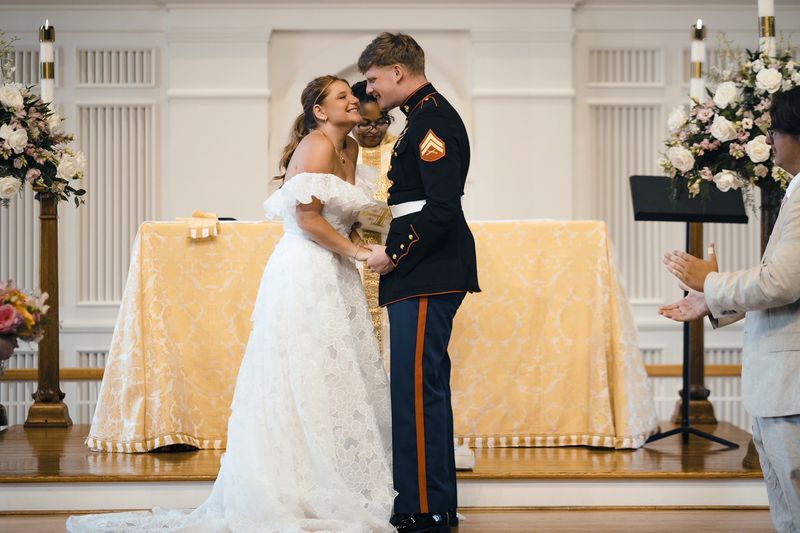 This image provided by Tell It Well Photography shows Gwyneth Collart, left, and Cpl. Jonah Waser at the alter during their wedding, July 6, 2024, in Arlington, Va. Collart is the sister of the late Marine Corporal Spencer R. Collart, who was killed along with two other Marines when the MV-22B Osprey aircraft they were on crashed during drills on a north Australian island on August 27, 2023. (Tell It Well Photography via AP)