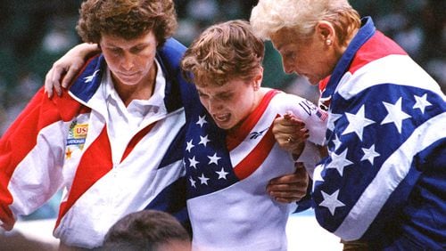 American Kerri Strug (middle) is helped after her final vault after hurting herself during the last routine in the team competition at the Georgia Dome. (AJC Staff Photo/Rich Addicks)