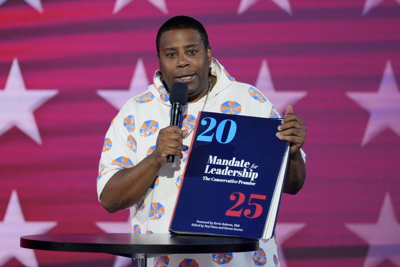 Kenan Thompson speaks as he carries a copy of Project 2025 on stage during the Democratic National Convention Wednesday, Aug. 21, 2024, in Chicago. (AP Photo/J. Scott Applewhite)