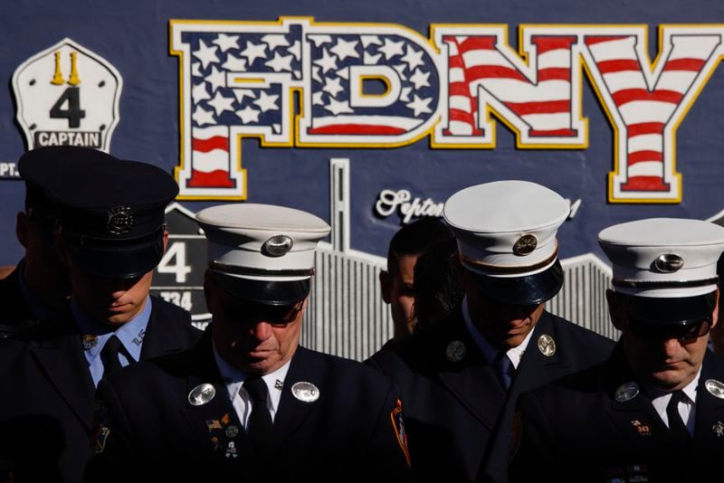 New York City firefighters bow their heads during a moment of silence outside Engine 4 Ladder 15 on the 23rd anniversary of the Sept. 11, 2001 terror attacks, Wednesday, Sept. 11, 2024, in New York. (AP Photo/Stefan Jeremiah)