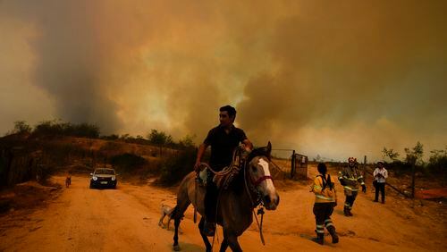 FILE - A resident flees an encroaching forest fire in Vina del Mar, Chile, Feb. 3, 2024. Police arrested a suspect on Friday, May 24, 2024, for allegedly causing the forest fire that left 137 dead and injured some 16,000 people in the Valparaíso region. (AP Photo/Esteban Felix, File)