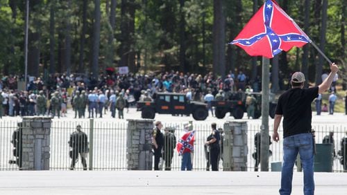 Joseph Andrews, one of a small group with the Rock Stone Mountain rally, waves a confederate battle flag towards a mass of counter-protesters more than 100 yards away at Stone Mountain Park on Saturday afternoon April 23, 2016 where a white power protest and two counter protests were scheduled. Ben Gray, bgray@ajc.com