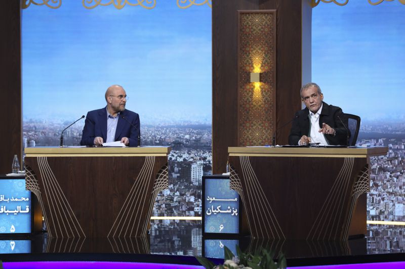In this picture made available by Iranian state-run TV, IRIB, reformist presidential candidate for the June 28 election Masoud Pezeshkian, right, speaks as another candidate Mohammad Bagher Qalibaf, listen to him in a debate of the candidates at the TV studio in Tehran, Iran, Tuesday, June 25, 2024. Iran's supreme leader Ayatollah Khamenei issued a thinly veiled warning Tuesday to the sole reformist candidate in the country's upcoming presidential election, saying anyone who believes "all ways to progress" come from the United States shouldn't be supported. (Morteza Fakhri Nezhad/IRIB via AP)