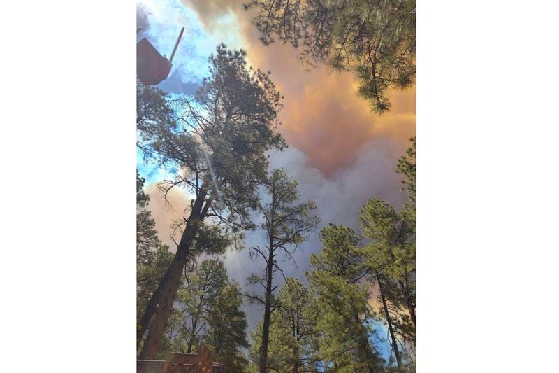 Smoke from a wildfire rises over trees in Ruidoso, N.M., Monday, June 17, 2024. Residents of the mountain village of about 7,000 residents fled their homes under evacuation orders with little time to rescue belongings. (Jacquie Escajeda via AP)