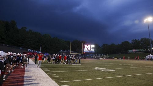 Storm clouds approach the stadium as the Milton defense huddles up against Buford in the first half at Milton High School, Friday, August 16, 2024, in Milton, Ga. (Jason Getz / AJC)