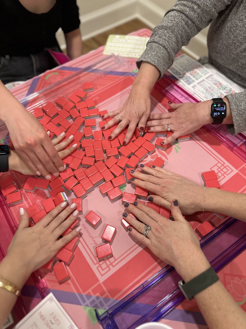 Mahjong takes its name from the clicking of the tiles, particularly visible when shuffling them, as the players do here.  (Courtesy of Let's Rack and Roll)