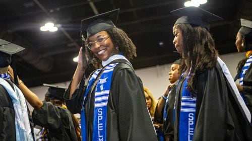 Graduates help each other don hoods at the commencement ceremony at Morehouse College in Atlanta on Sunday, May 19, 2024. (Arvin Temkar / AJC)